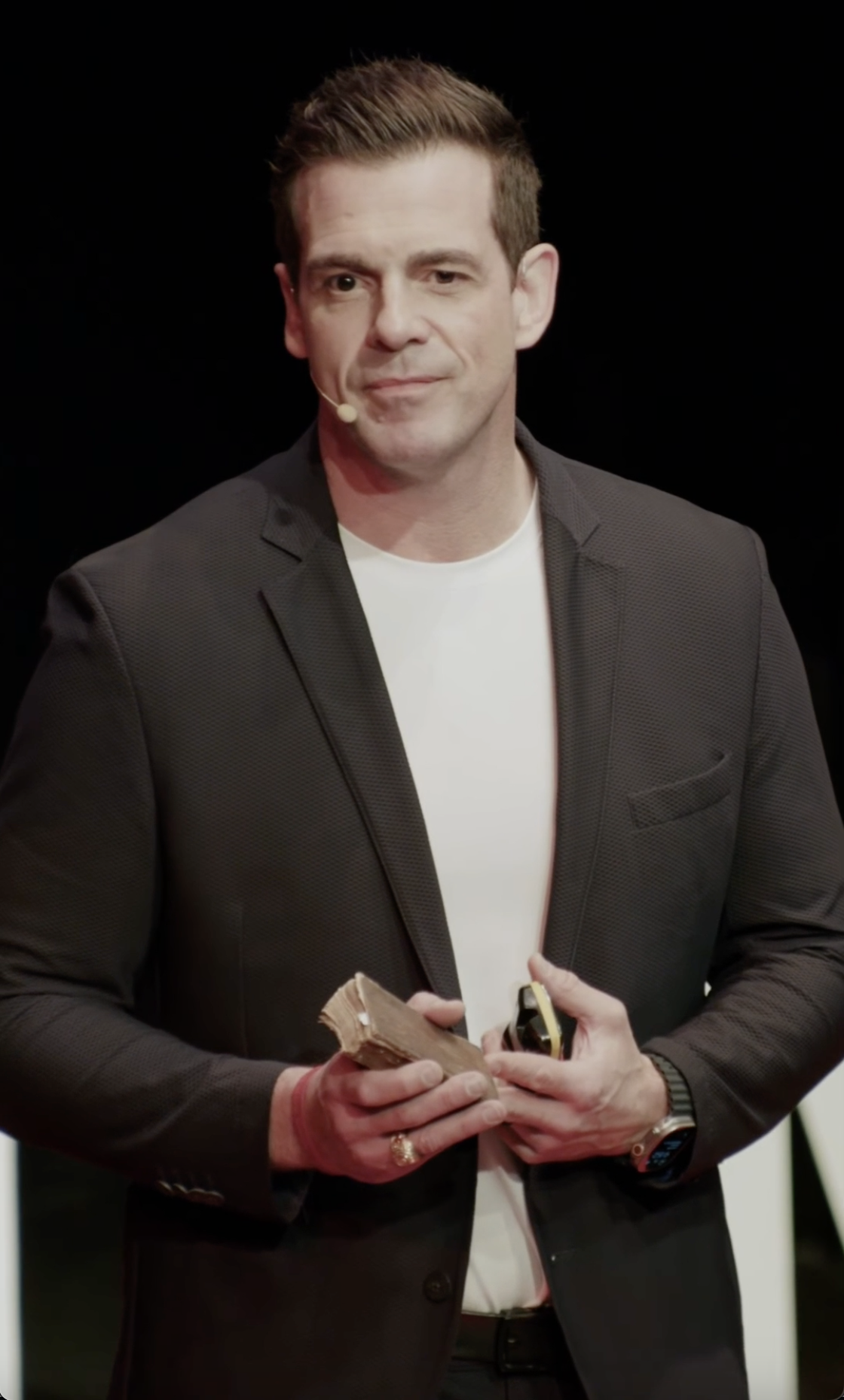 Chris Valletta on stage holding a soldier's pocket Bible